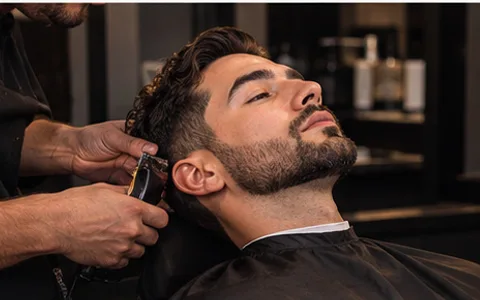 Perfilado de barba con máquina en el sillón de barbería