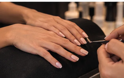 Aplicación de esmalte en manicure, mano apoyada en la mesa